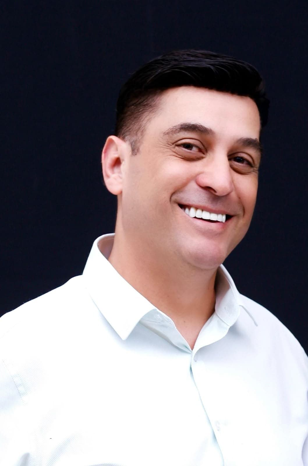 Emerson Costa, arquiteto e urbanista, sorrindo, de camisa branca